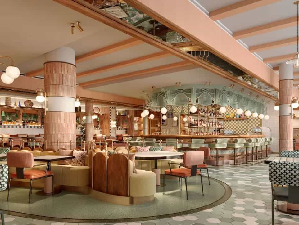 Elegant hotel restaurant area with pastel pink and green decor and hanging lights. 