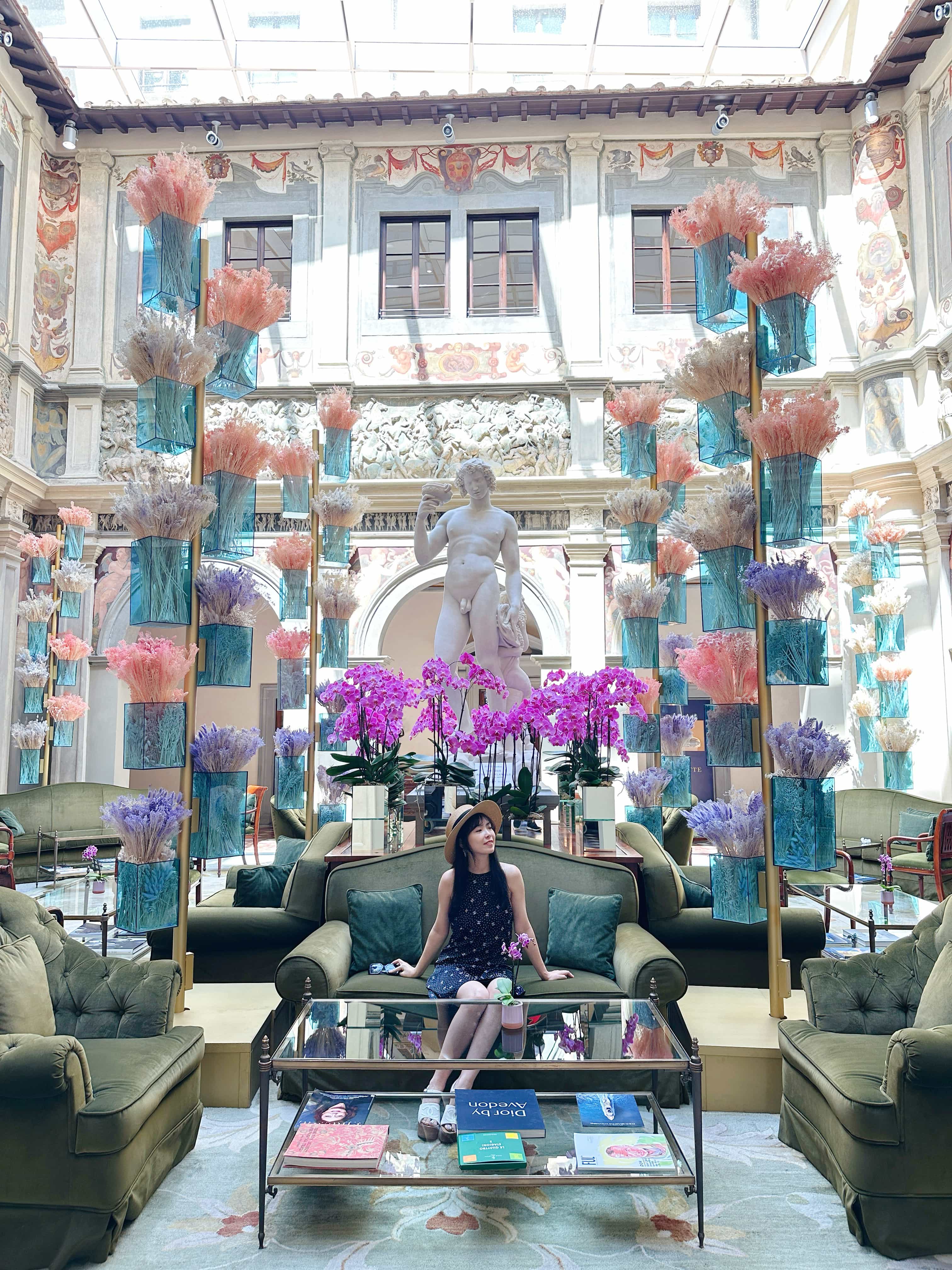 Advisor sitting on an upholstered couch in a hotel lobby with glass walls and a white statue of a man behind her