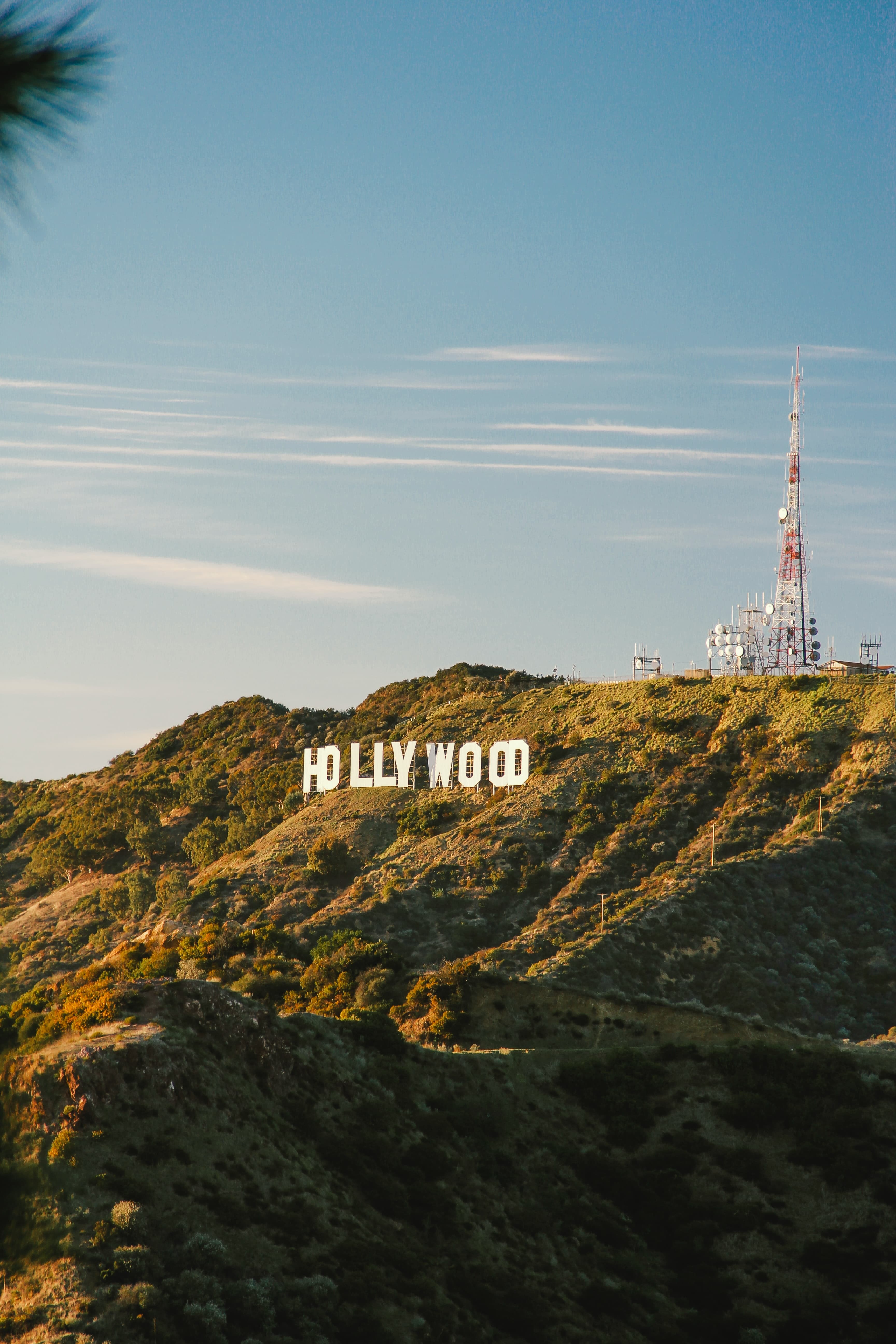 green mountain with large white sign during daytime