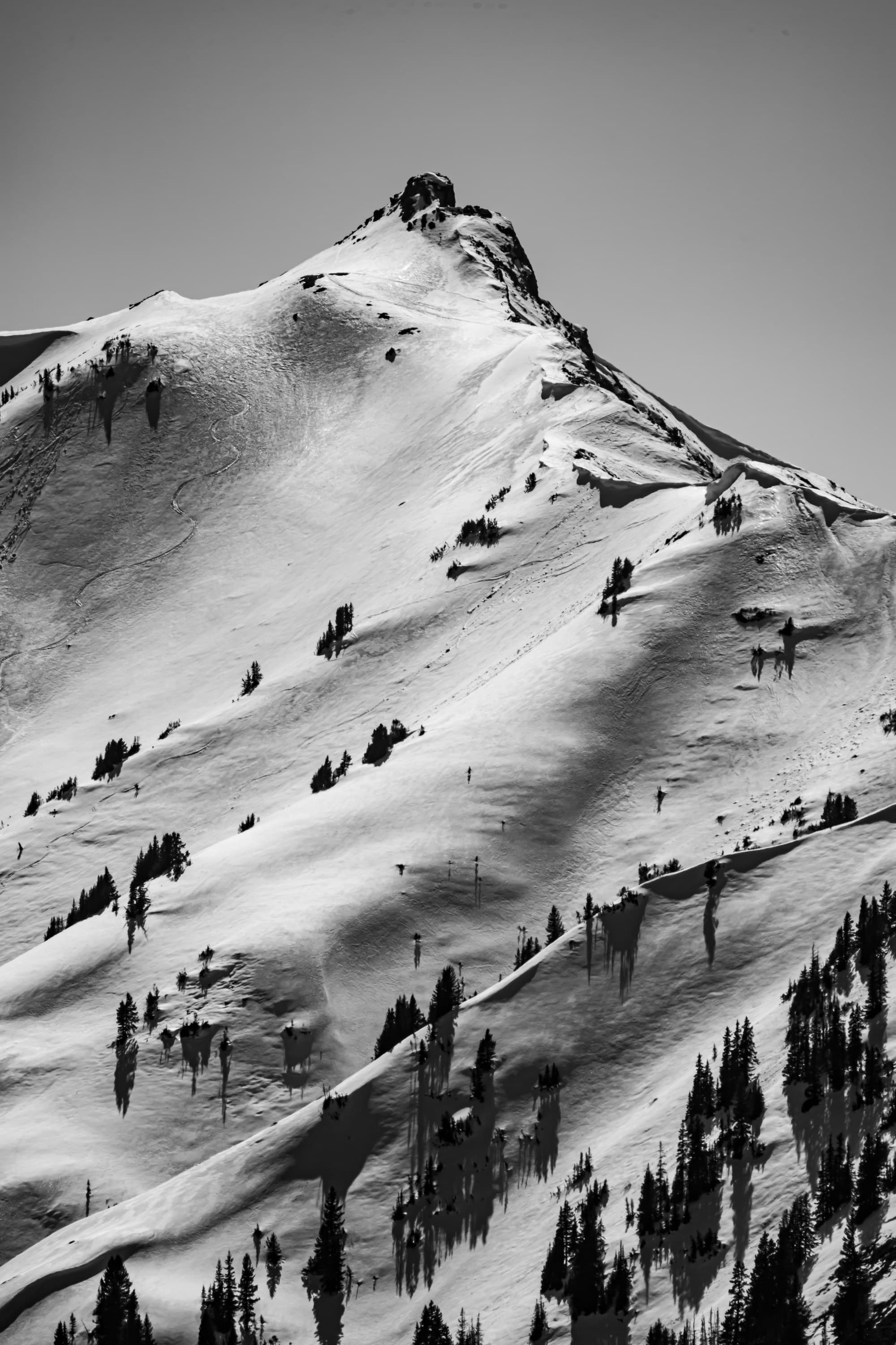 Greyscale photo of people walking on a snow covered mountain.