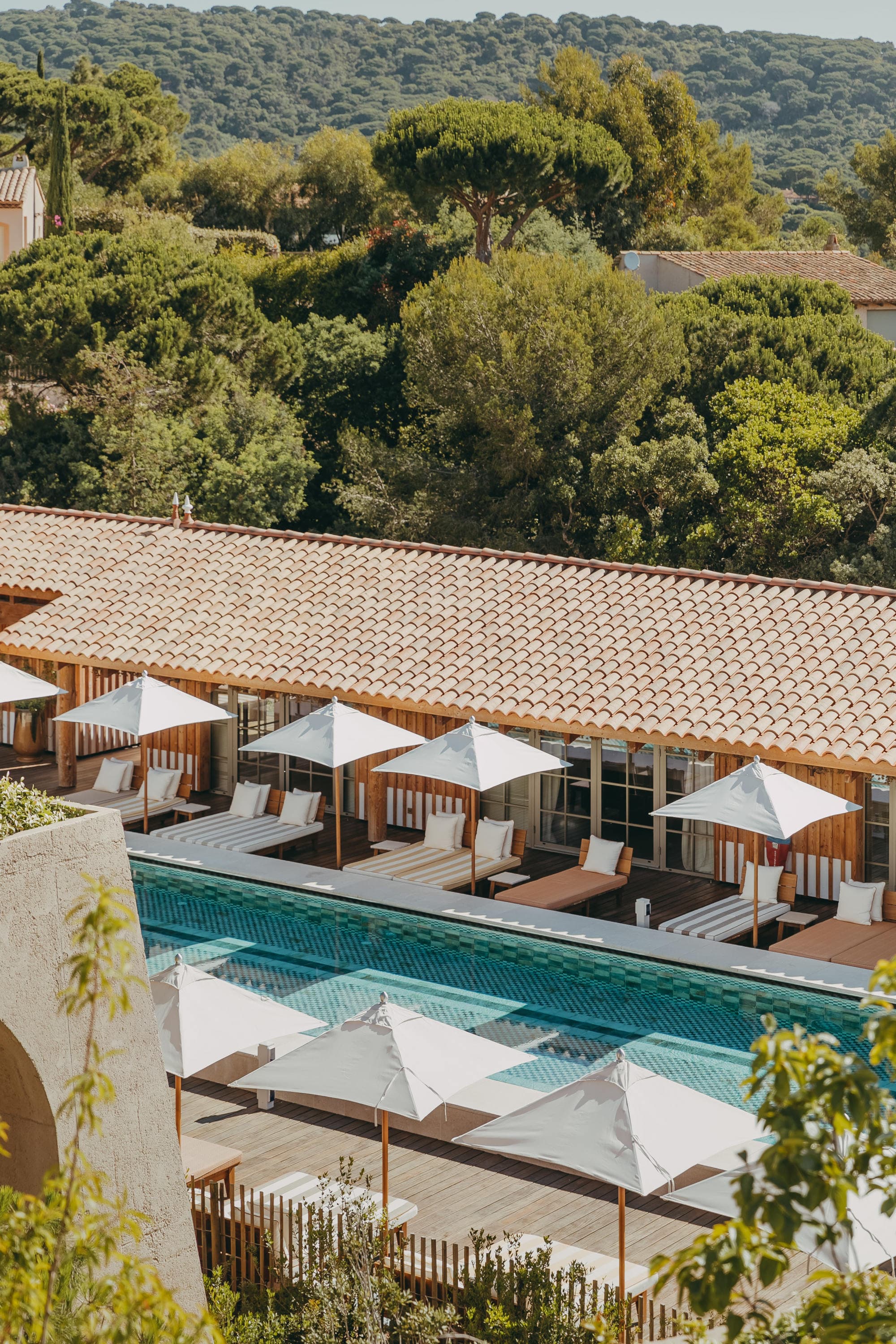 aerial view of a sleek swimming pool surrounded by loungers and white sun umbrellas