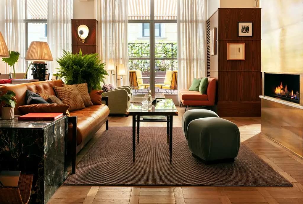 a hip living room with a yellow leather couch and two green poof seats around a black coffee table