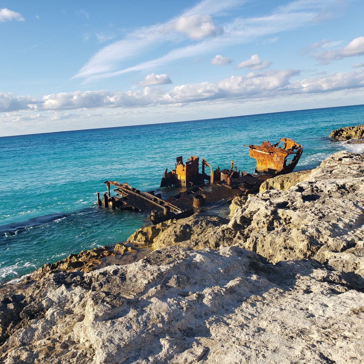 Rusty boat sitting on rocky beach during daytime